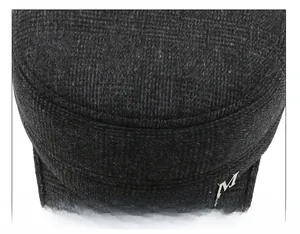 Dettaglio della cucitura del cappello di lana con emblema a lettera M in metallo