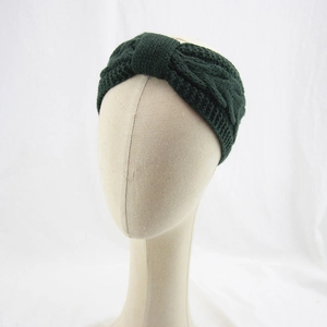 Detail of dark green knit headband with cable pattern and bow on a model head