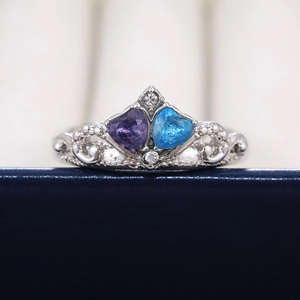 Macro detail of crown ring featuring heart-shaped blue and purple stones on jewelry box