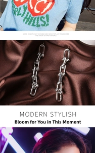 Detailed view of silver U-shaped industrial chain earrings on brown silk background
