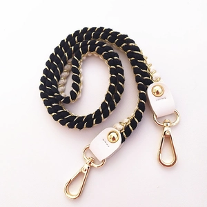 Detailed view of woven black and white cotton strap with gold metallic thread and hardware