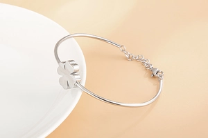 Detail of clover bangle featuring a polished metal half-ring with adjustable chain