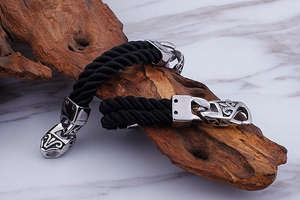 Detail of double-layer black nylon rope bracelet with engraved steel clasp on wood