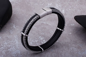 Detail of layered black leather and silver braided chain bracelet with magnetic clasp