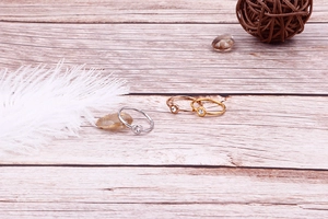 Three-color minimalist titanium steel rings with cubic zirconia on a wooden surface