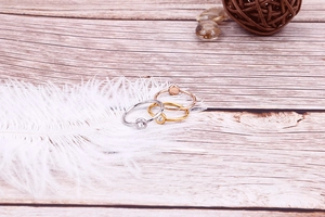 Detailed view of three minimalist rings in silver, gold, and rose gold with tiny zircons