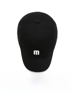 Top down view of black cotton baseball cap featuring white embroidered letter m logo detail