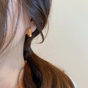 Chic gold-tone geometric U-shaped earrings worn by a model in a side-profile view
