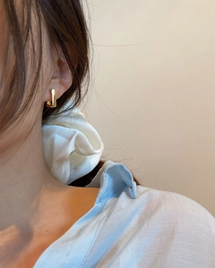 Close-up of elegant gold geometric rectangular huggie earring worn by a model