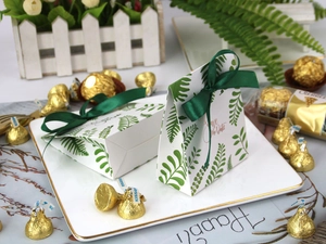Close-up of European wedding candy box with green fern patterns and dark green satin ribbon