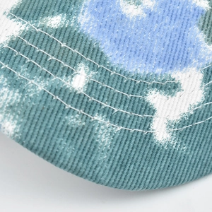 Detailed macro view of tie-dye cotton fabric with precise triple-row stitching on brim