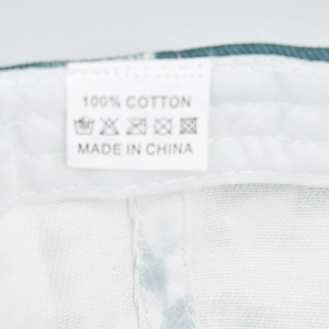 Detailed view of the 100% cotton material tag and washing instructions on a tie-dye cap