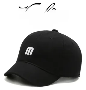 Detail of black cotton baseball cap showing white 3D m embroidery and twill texture