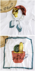 Detail of silk square scarf with tree cup illustration and smooth texture on white dress