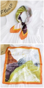 Close-up of landscape print silk scarf with bird motifs and vibrant orange edges