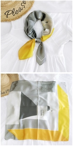 Detail showing a geometric print silk square scarf in grey and yellow on a white shirt