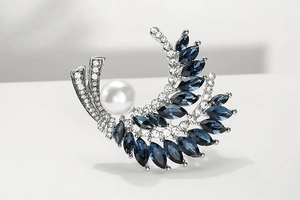 Details der silbernen Brosche mit blauen Markis-Kristallen und einer großen weißen Perle