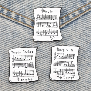 Détails de trois pins en émail partitions avec citations sur tissu denim bleu