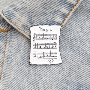 Détail de la broche en émail partition de musique sur un tissu en denim bleu clair