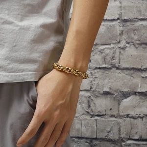Close-up of a bold gold stainless steel double buckle chain bracelet on a male wrist