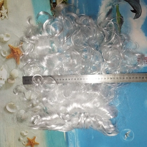 Macro shot showing wavy white Santa wig length with a ruler on a summer beach background