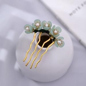 Close-up of golden U-shaped hair fork with light green flowers and white pearls