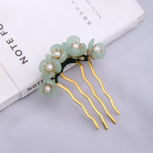 Detail of handmade flower hair fork with green petals, pearls, and golden metal comb