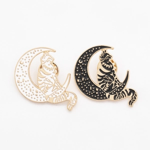 Detail view of cat on moon enamel brooches in black and white with butterfly pin clutch