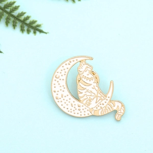 Detail view of a cat on moon enamel pin with gold plating on light blue background