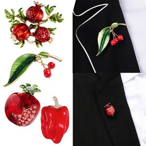 Elegant enamel fruit brooches featuring cherry and pomegranate designs on a suit lapel