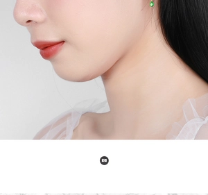 Detailed view of emerald green teardrop tassel earrings worn by a model in gold finish