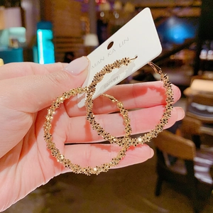 Close-up of gold chunky textured hoop earrings with S925 silver needles held by hand
