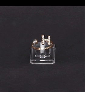 Vista macro dell'anello dorato a forma di H con strass bianchi e fascia regolabile