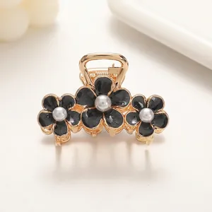 Detail view of triple floral hair claw clip with black petals and central pearls