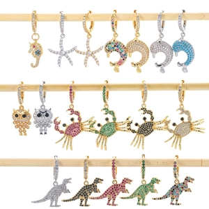 Dettaglio di orecchini ad animali con zirconi colorati su espositori in legno chiaro