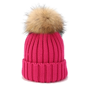 Nahaufnahme der rosaroten Strickmütze mit einem flauschigen braunen Kunstpelz-Pompon