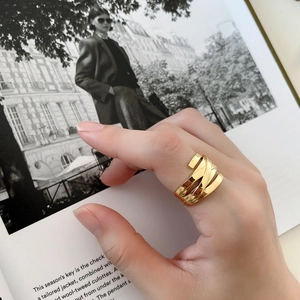 Close-up of golden multi-layer braided silver ring worn on a finger over a fashion magazine