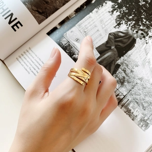 Polished gold multi-layer woven ring shown on hand with a modern magazine background