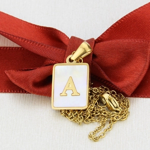 Detail view of square shell pendant featuring a gold letter A on a polished gold chain