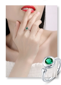 Detail shot of an adjustable silver ring featuring a round green moissanite stone