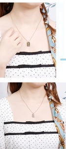 Détail d'un collier pendentif carré doré avec étoile chanceuse et lettres gravées