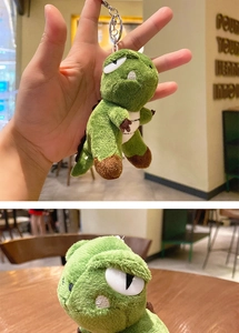 Close-up of green plush dinosaur doll keychain with durable metal clasp for bags