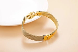 Détail d'un bracelet en maille dorée avec un charm ancre centrale sur fond clair