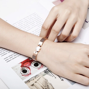 Rose gold metal mesh bracelet with white heart charm shown on model wrist