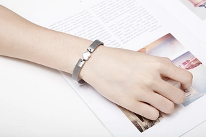 Detailed macro view of a silver mesh strap bracelet featuring a white heart charm