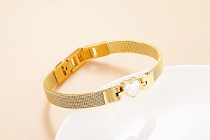 Detailed macro view of the gold mesh bracelet strap and a white heart-shaped shell inlay