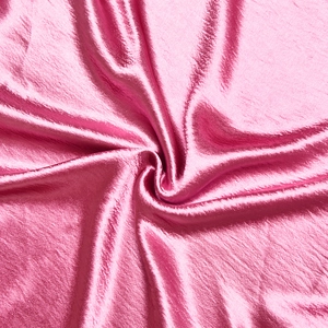 Détail du tissu en satin rose avec une finition brillante et des plis élégants et doux