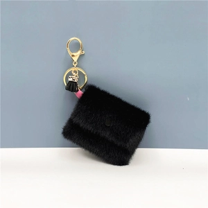 Detailed macro of black faux fur mini coin pouch with gold metal swivel hook and tassel