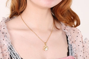 Close-up of a delicate 18K gold plated necklace featuring a sparkling diamond cat paw pendant