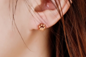 Gros plan d'une boucle d'oreille patte en or rose portée par un mannequin femme